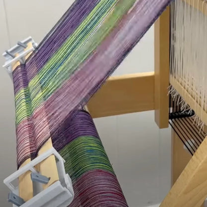 LoftyFiber Helping Hands am Louet Jane Tischwebstuhl – Kettfadenhalter mit buntem lila-grünem Webgarn auf dem Webstuhlbaum