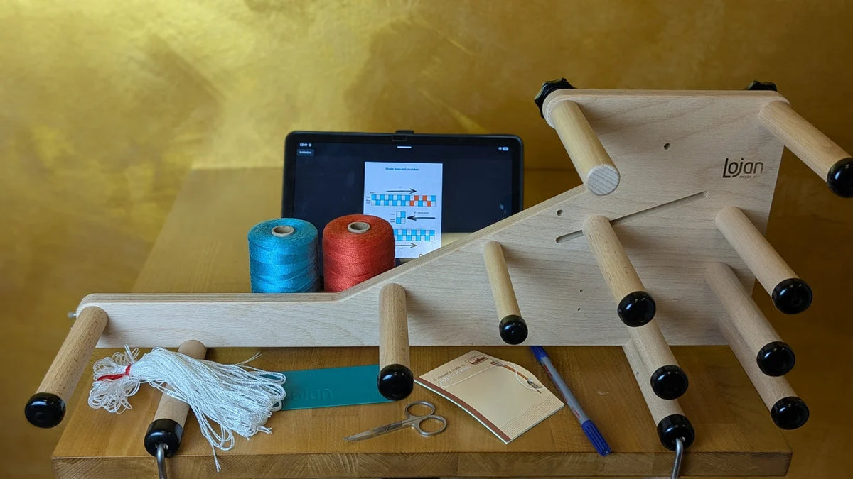 Online-Videokurs Bändchenweben: Lojan Inkle Loom mit Tencel-Garn, Litzen, Schiffchen und Workbook auf dem Tisch