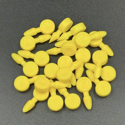 Texsolv Pfeilstecker in Gelb – Kunststoffstecker zur Fixierung von Texsolv Ösenschnur, rundes Design, auf dunkler Oberfläche lose angeordnet