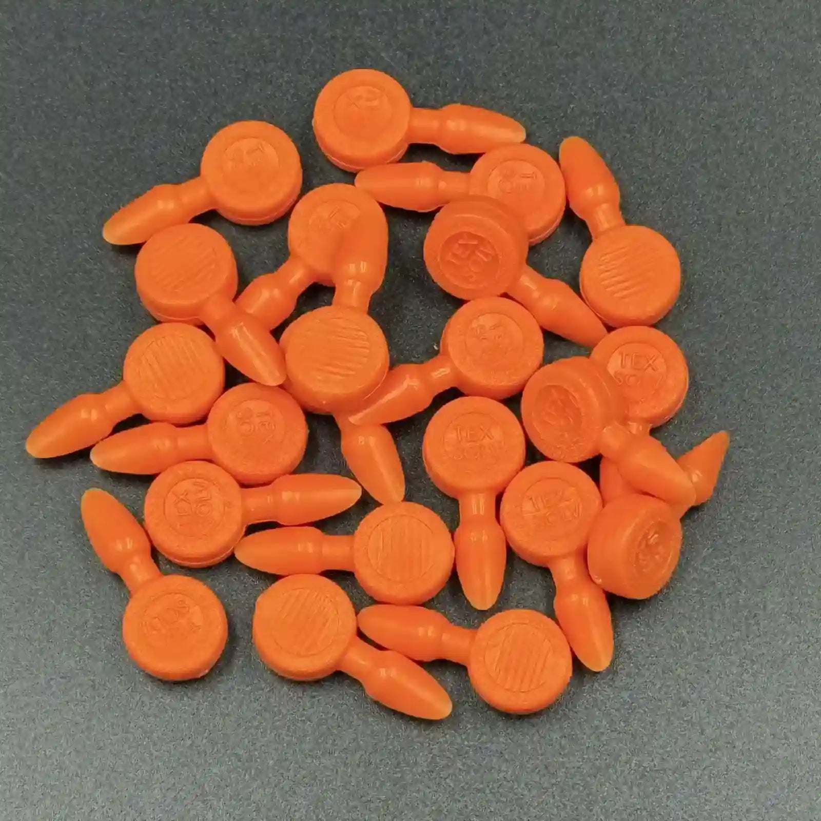 Texsolv Pfeilstecker in Orange – runde Kunststoffstecker zur Befestigung von Texsolv Ösenschnur am Webstuhl, flach auf dunklem Untergrund angeordnet