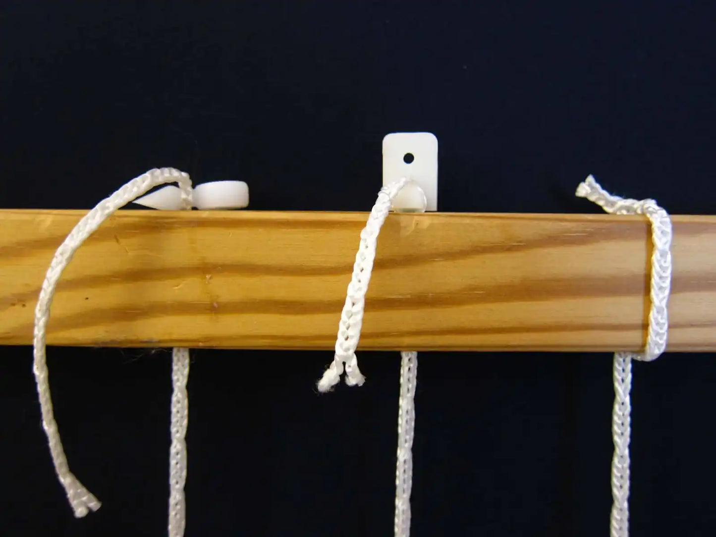 Texsolv Pfeilstecker in Anwendung - befestigt Texsolv Ösenschnur an einem Holzrahmen des Webstuhls zur Fixierung von Schaftverschnürungen